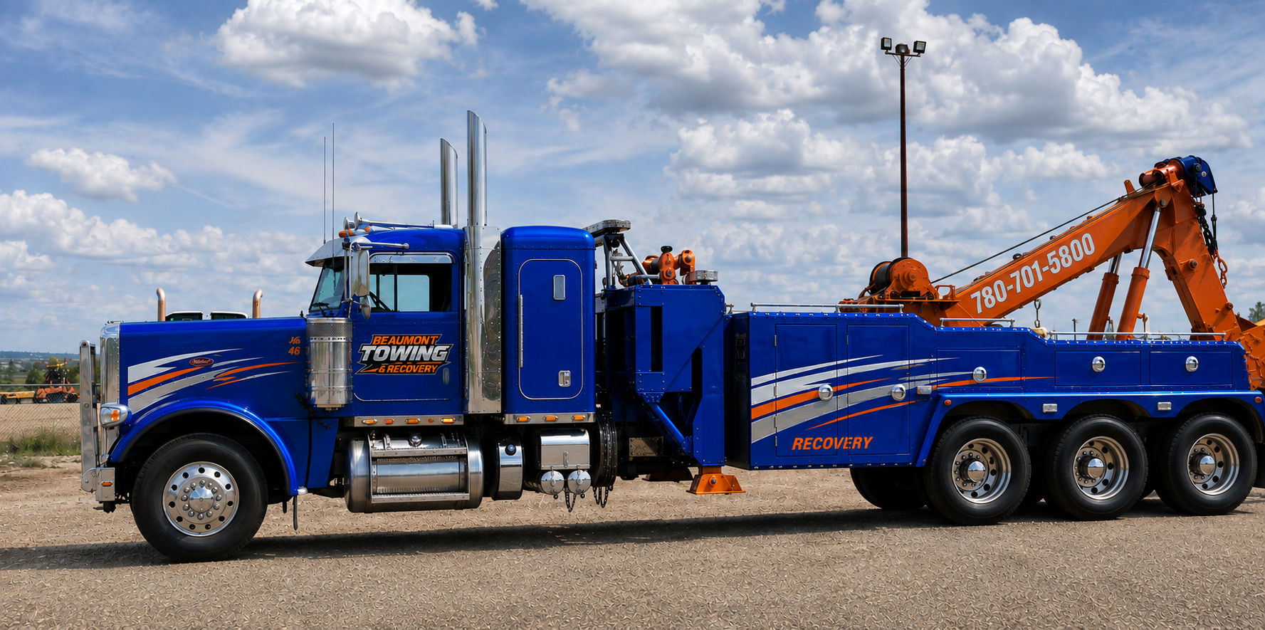 Blue Beaumont Towing & Recovery heavy-duty wrecker parked under an open Alberta sky